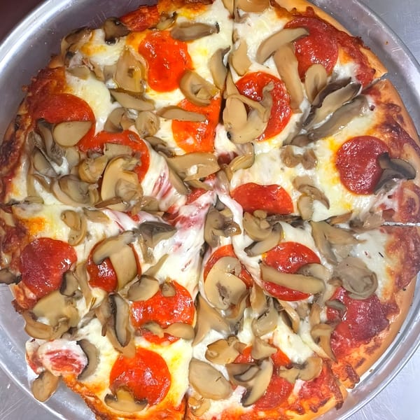 A close-up, overhead view of a freshly baked Jimmy Neno's pepperoni and mushroom pizza.