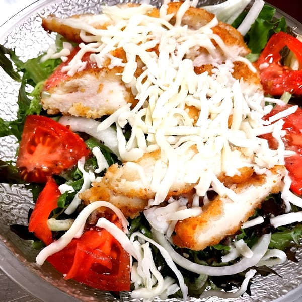 Crispy chicken cutlets, shredded mozzarella, tomatoes, and onions on a bed of fresh greens.